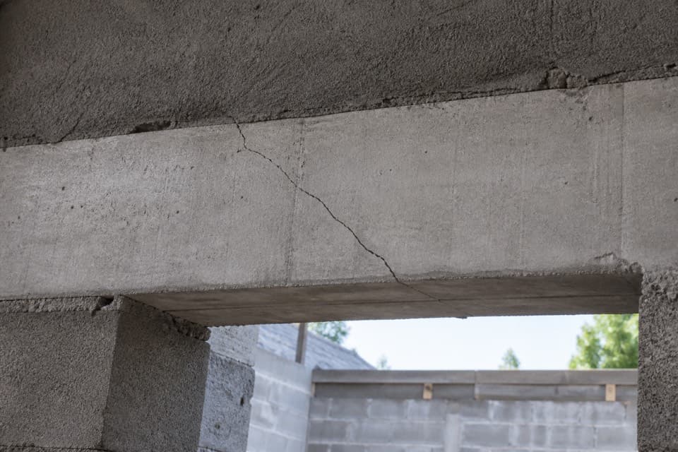 Linteau en béton avec une fissure visible au-dessus d’une ouverture